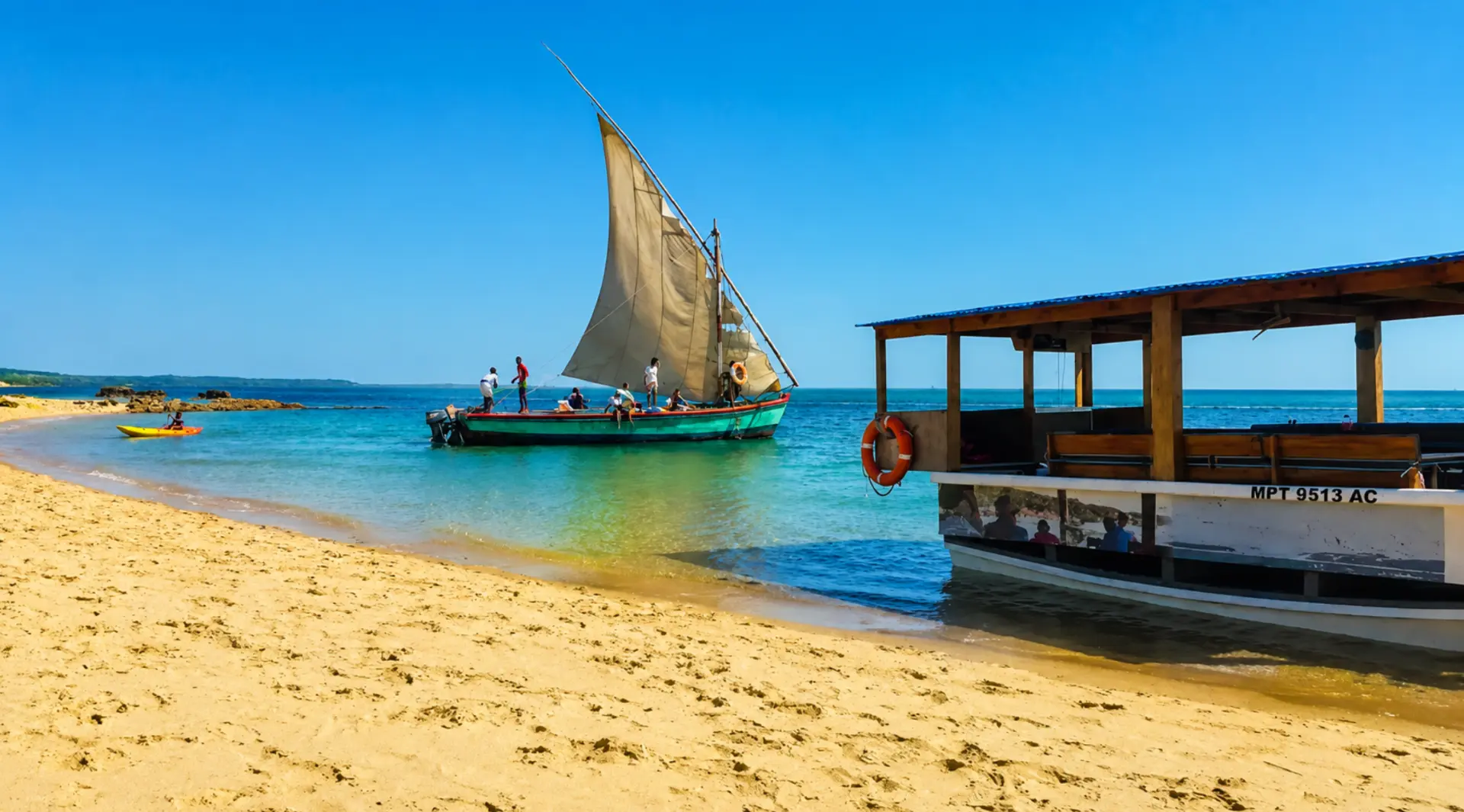 Traditional dhow and tour boat moored on a turquoise Santa Maria beach under a blue sky