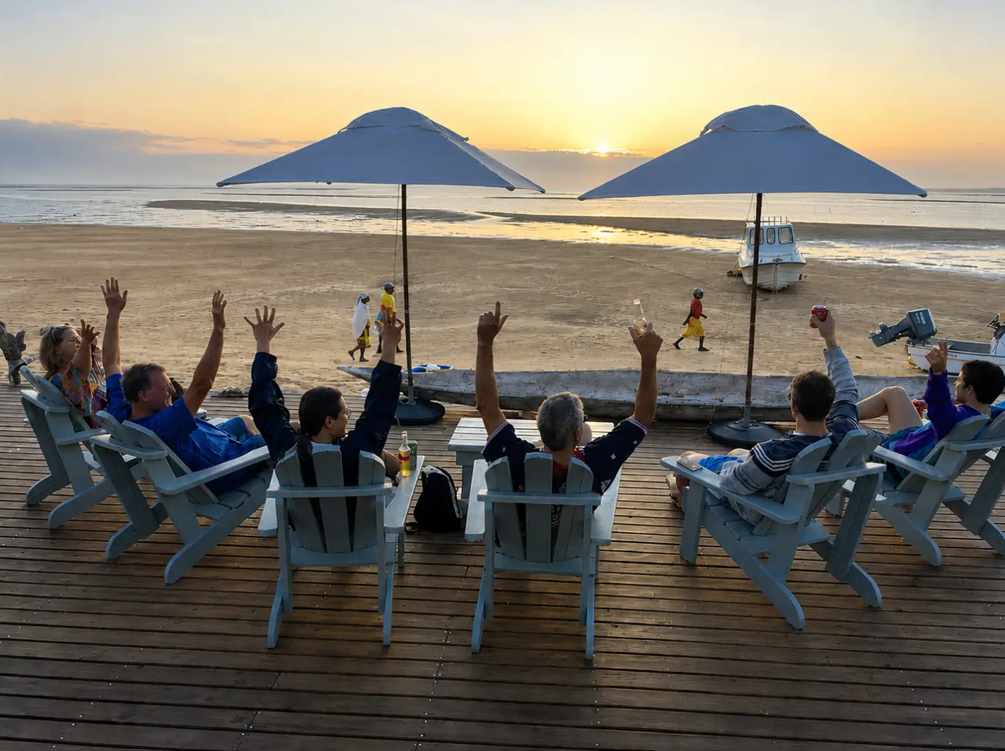 Guests on the Bemugi's deck raising their hands to a Santa Maria sunset